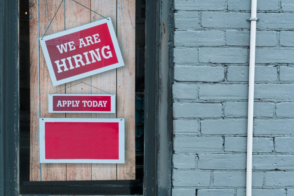Hiring signs in a storefront window with messages like ‘We Are Hiring’ and ‘Apply Today’, representing opportunities in the Canadian job market.